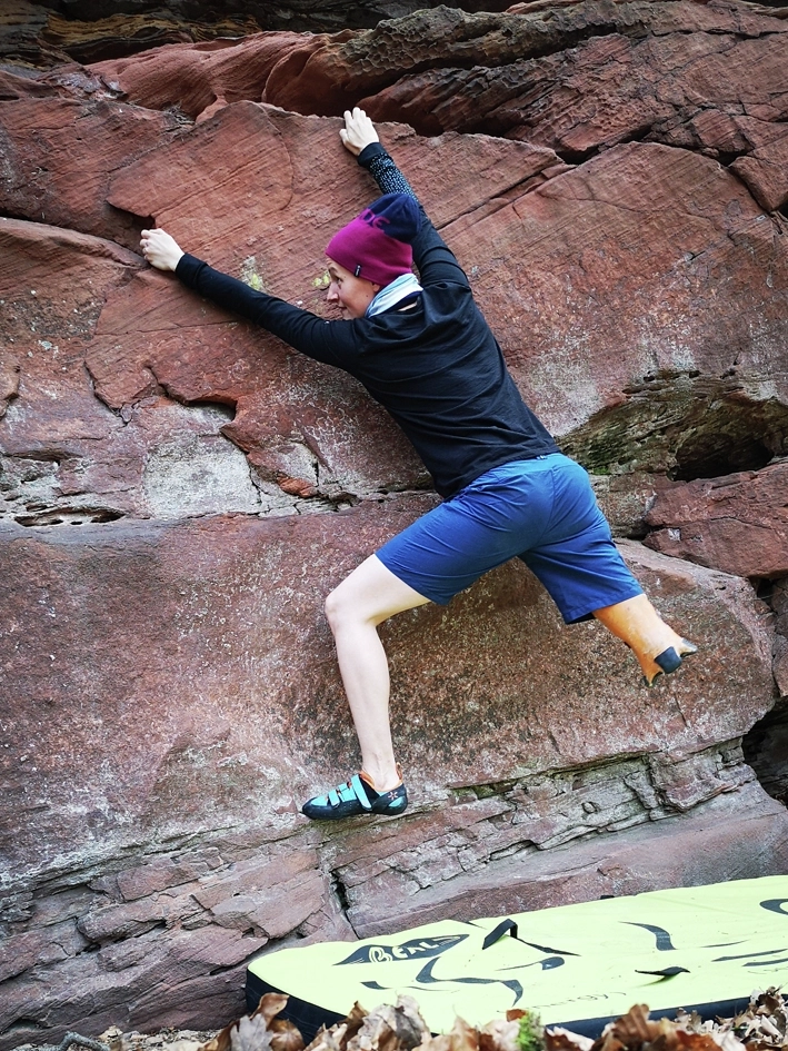 Eine junge unterschenkelamputierte Frau klettert in einer Felswand