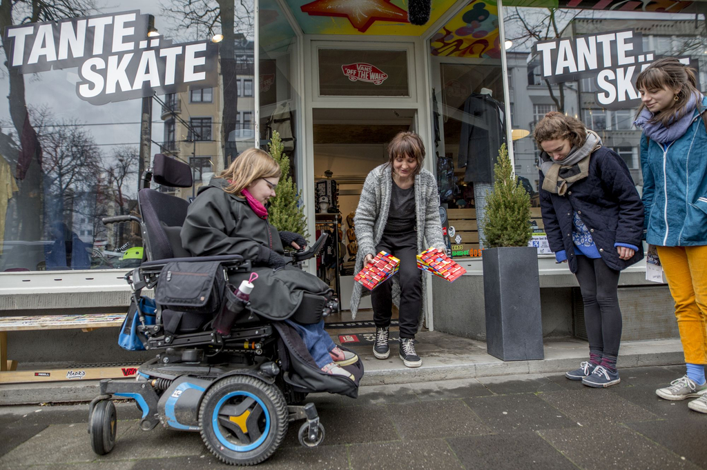 Caro übergibt mit weiteren Teilnehmerinnen des Legorampen-Projekts eine selbstgebaute Rampe an die Besitzerin eines Skateshops.