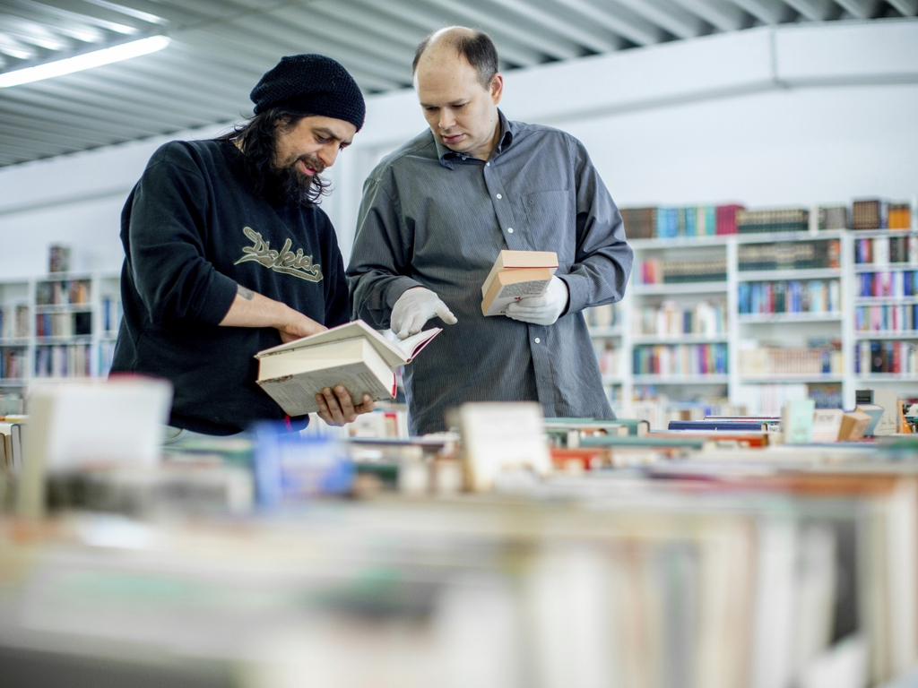 Zwei Männer schauen gemeinsam Bücher im Basar durch.