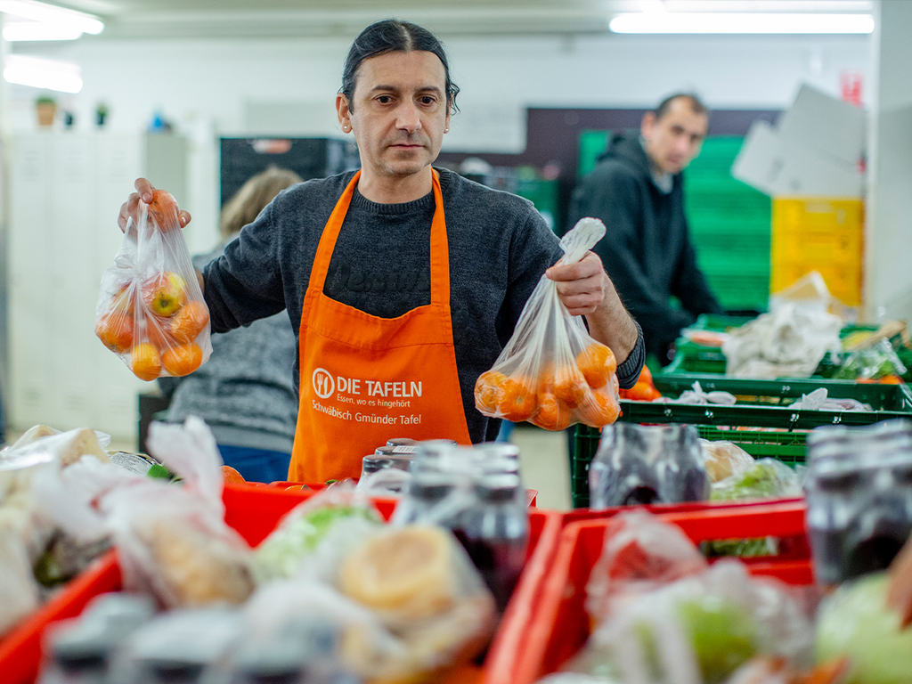Ein Mann packt Obst und Gemüse in Kisten.
