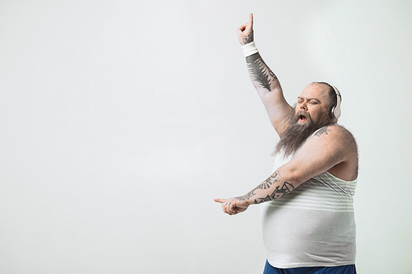 Ein tanzender Mann mit Kopfhörern. An den Armen ist er tätowiert.