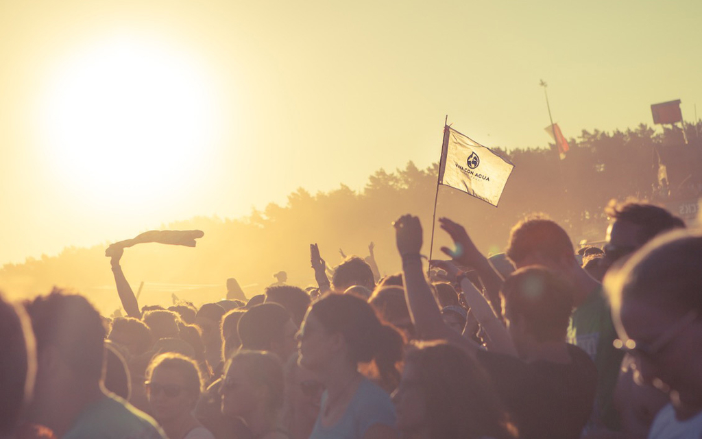 Festivalstimmung: Die VcA-Fahne weht über den Köpfen der feierenden Menge und ist in Sonnenlicht getaucht.