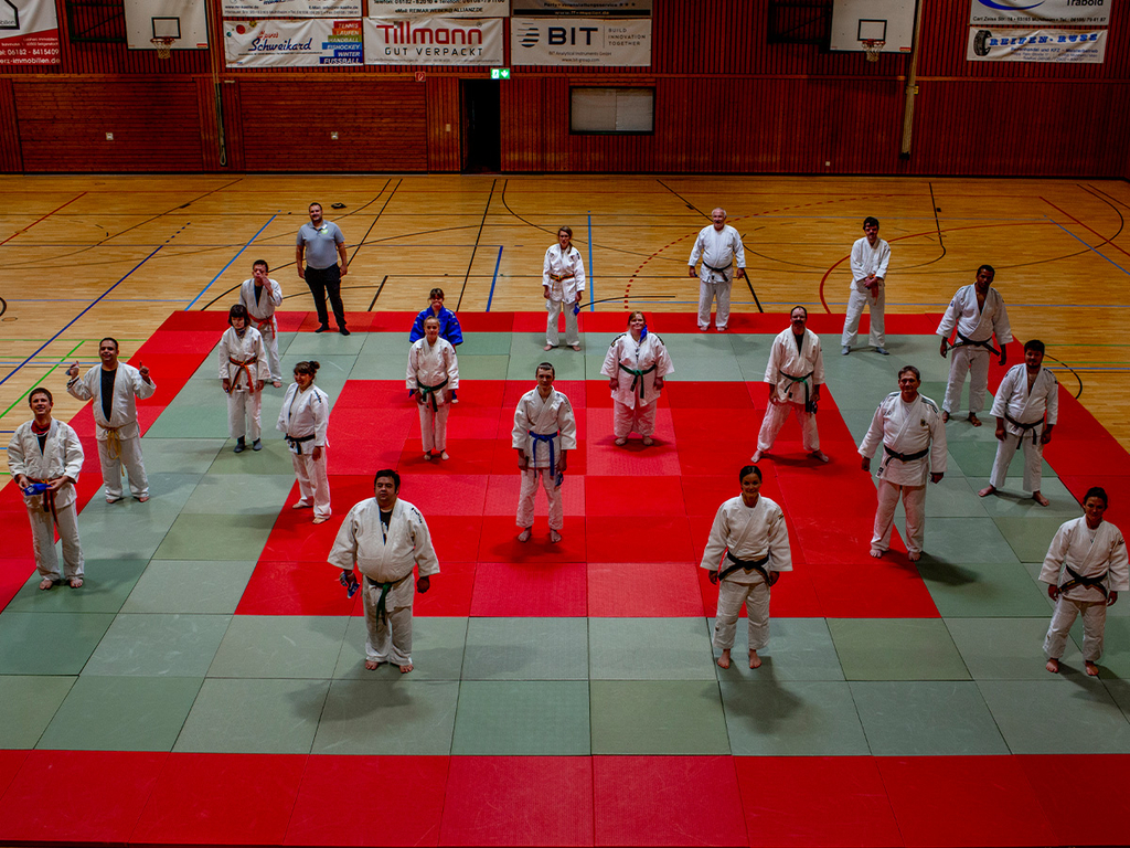 Die Trainingsteilnehmer*innen stehen auf den Judomatten für ein Gruppenfoto.
