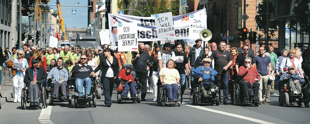 Menschen mit Behinderung bei einem Protestzug durch eine Stadt.