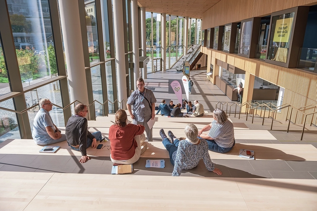 Zwei Kleingruppen tauschen sich jeweils aus in einem großen Atrium.