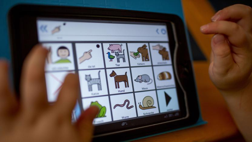 Kinderhände vor einem Tablet mit mehreren Symbolen für Tiere. Zum Beispiel, Hund, Katze, Maus, Schnecke. 