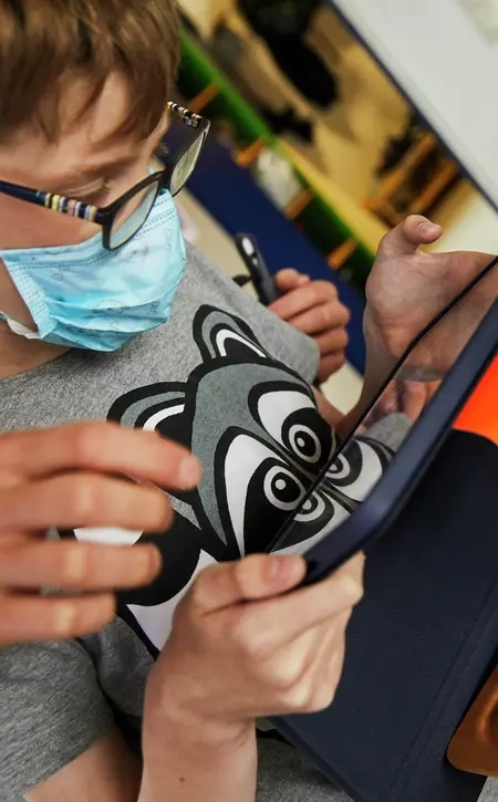 Ein Junge scannt mit einem Tablet einen QR-Code ein.