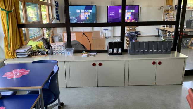 Blick durch eine Glaswand von einem Klassenzimmer in ein anderes. Im hinteren Zimmer hängen zwei Smartboards an der Wand.