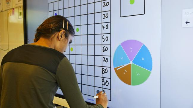 Ein Mädchen trägt auf dem Smartboard eine Zahl in eine Tabelle ein.