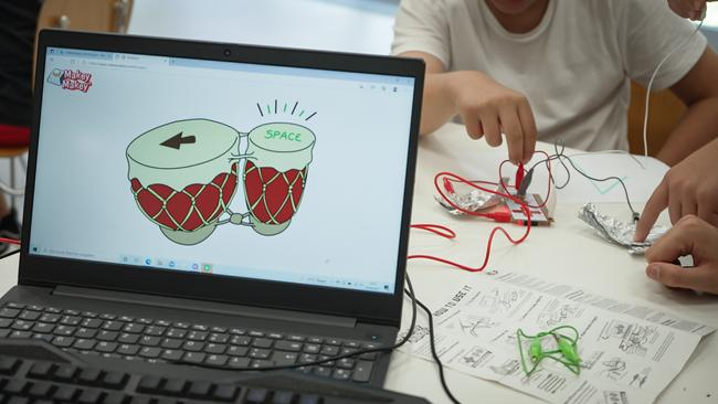 Auf einem Tisch steht ein Laptop. Auf dem Bildschirm sieht man die Zeichnung von zwei Trommeln. Im Hintergrund sind Hände und Elektronik-Kabel zu sehen.