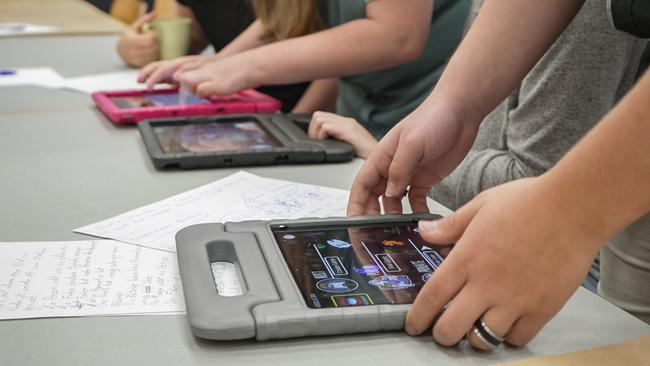 Drei Tablets, die nebeneinander auf einem Tisch liegen. An jedem Tablet sind Hände zu sehen.