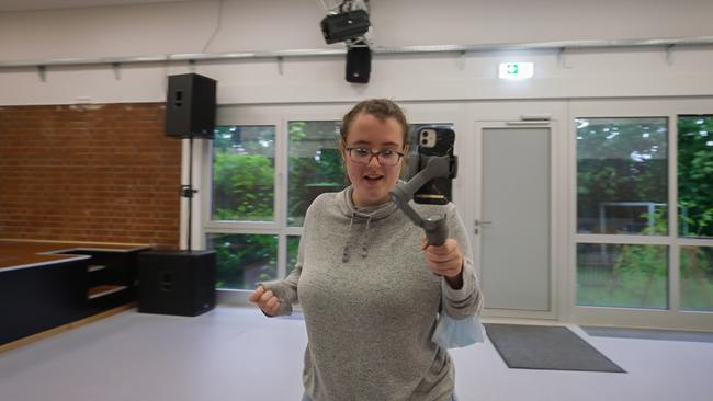 Eine junge Frau hält einen Selfiestick mit einem Handy in der Hand.
