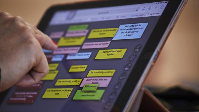 Ein Tablet mit verschiedenen Aussagen zum Thema Nachhaltigkeit und eine Hand, die ein Thema auswählt.