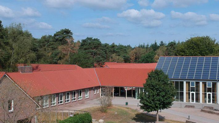Mehrere Gebäudeteile der Waldschule Hatten aus der Luft fotografiert. Auf einem Gebäudeteil ist eine Solaranlage angebracht.