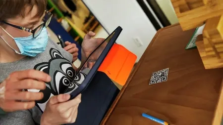 Ein Junge scannt mit einem Tablet einen QR-Code ein.