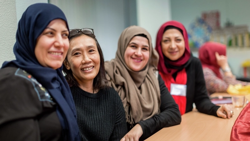 Vier Frauen, drei davon mit Kopftuch, sitzen an einem Tisch.