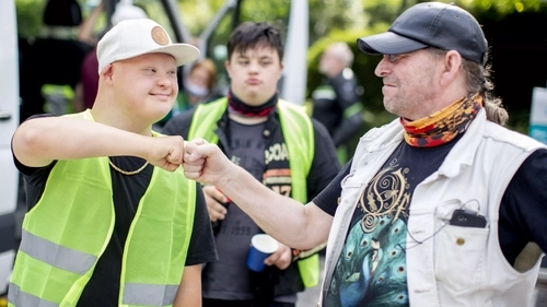 Ein Mann mit Downsyndrom begrüßt einen anderen Mann freundschaftlich mit einem Faust-Gruß. Beide gehören zu einem Motorradclub.