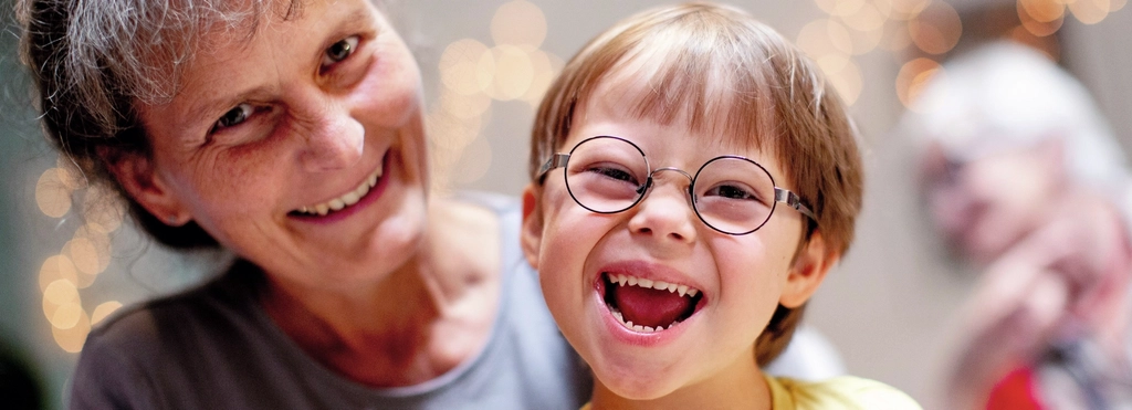 Eine Frau und ein lächelnder Junge mit Down-Syndrom