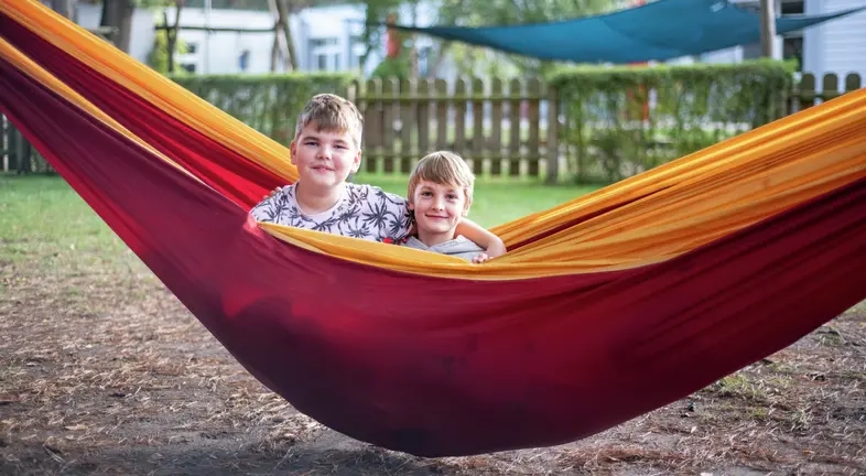 Zwei Jungs sitzen in einer rot-gelben Hängematte.