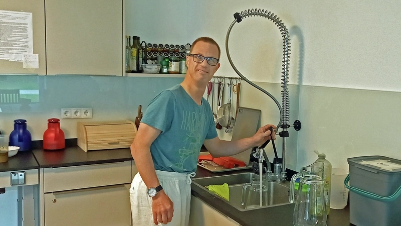 Ein junger Mann mit geistiger Behinderung in einer Küche