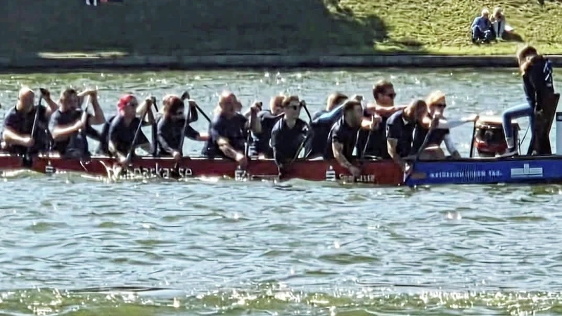 Ein Team aus zahlreichen Personen paddelt gemeinsam in einem Drachenboot