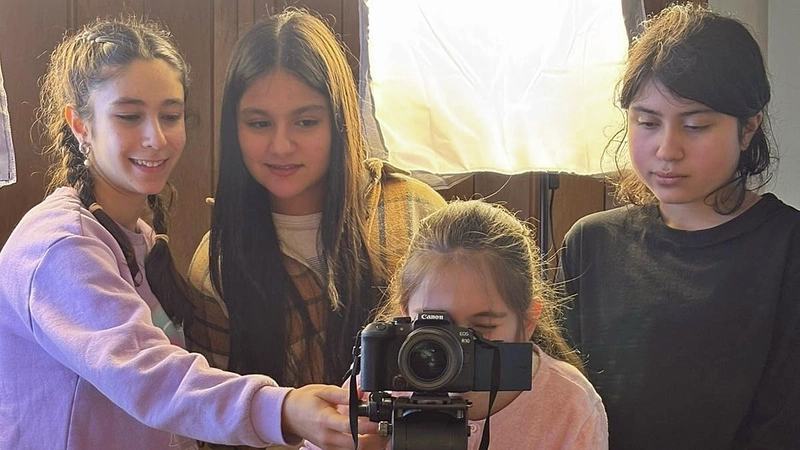 Vier Mädchen arbeiten mit einer Kamera, die auf einem Stativ steht