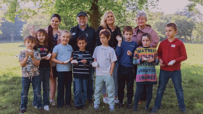 Gruppenbild mit Kindern und vier Erwachsenen auf einer Wiese