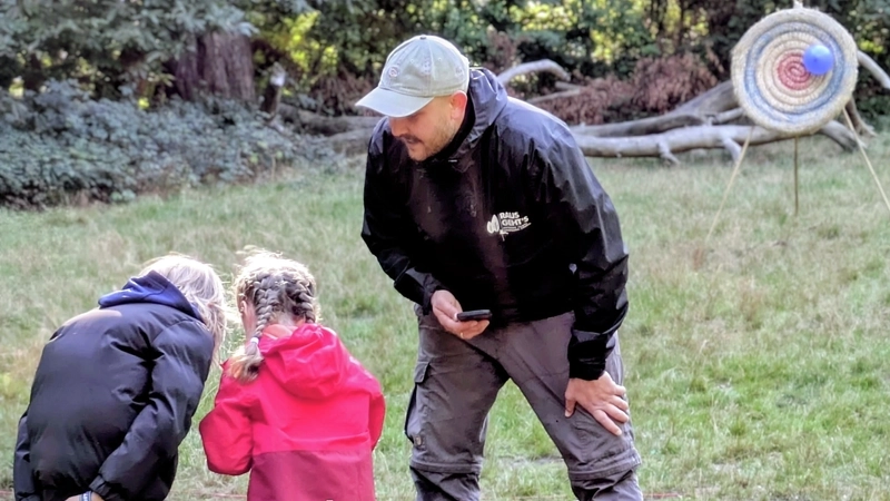 Zwei Mädchen und ein Mann bei einem Spiel auf einer Wiese
