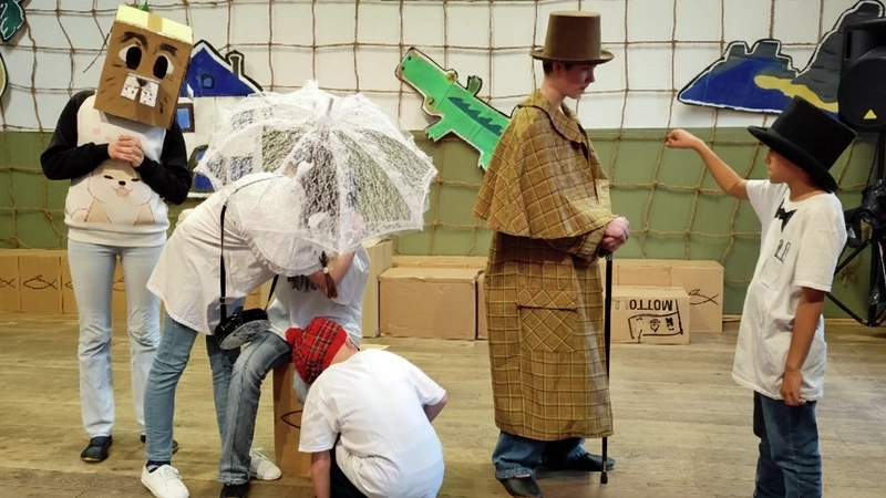 Fünf Kinder in Kostümen und Masken in einer Theaterszene