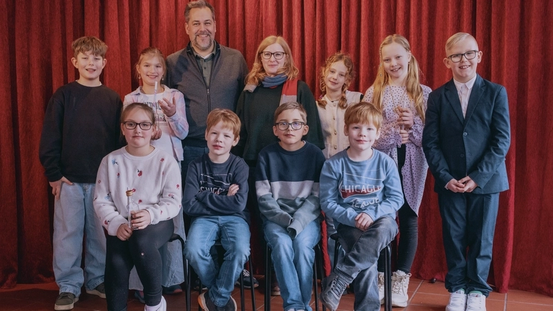 Gruppenbild mit mehreren Kindern und einem Mann vor dem Vorhang einer Bühne
