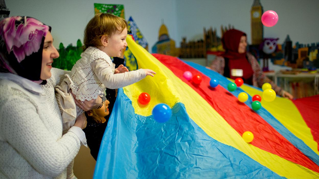 Mütter und Kinder spielen mit einem bunten Bälletuch