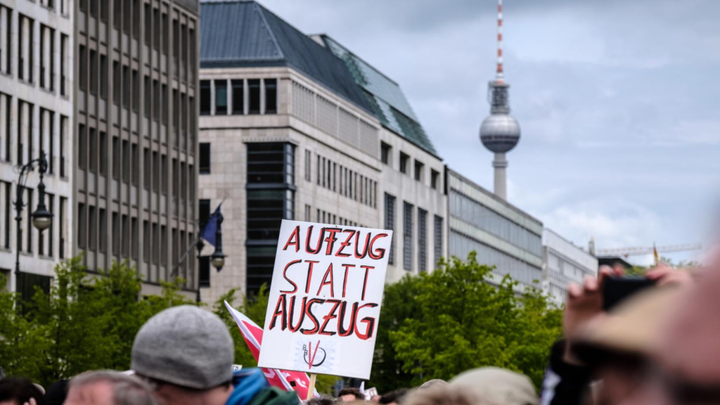 Demoschild mit der Aufschrift "Aufzug statt Auszug" ragt über die Köpfe von Demonstrierenden