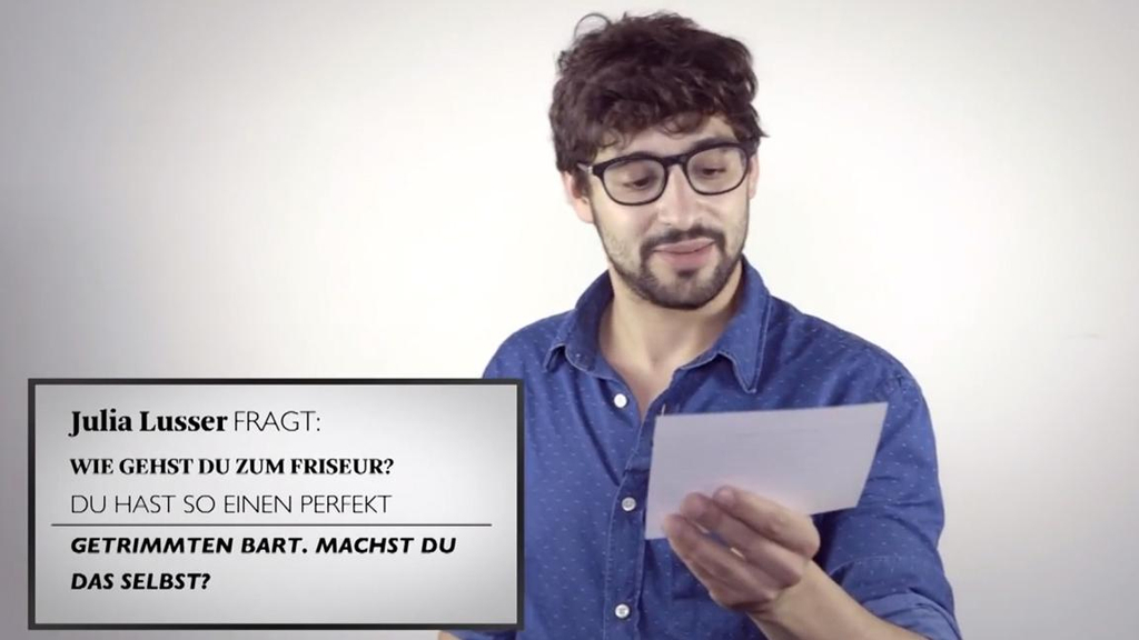 Bijans liest seine Frage ab, die eingeblendet ist. Sie lautet: Wie gehst Du zum Friseur? Du hast so einen perfekt getrimmten Bart. Machst Du das selbst?