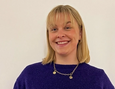 Porträt einer blonden jungen Fau, die eine Rose und ein Zertifikat hält