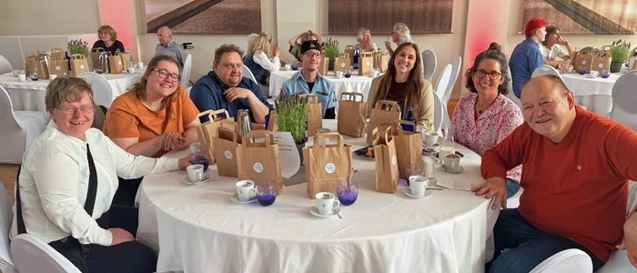 Sieben Personen mit und ohne Behinderung sitzen in einer Gaststätte um einen Tisch