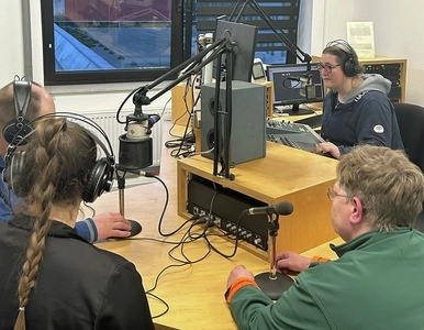 Vier Personen sitzen um einen Tisch und nehmen einen Podcast auf