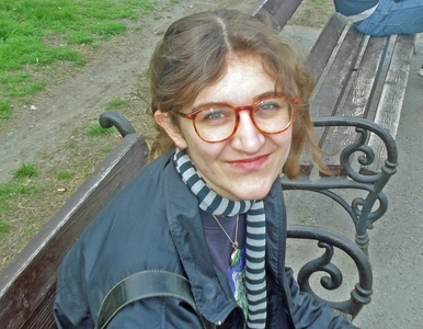 Porträt einer jungen Frau mit Brille auf einer Parkbank