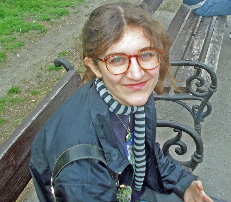 Porträt einer jungen Frau mit Brille auf einer Parkbank