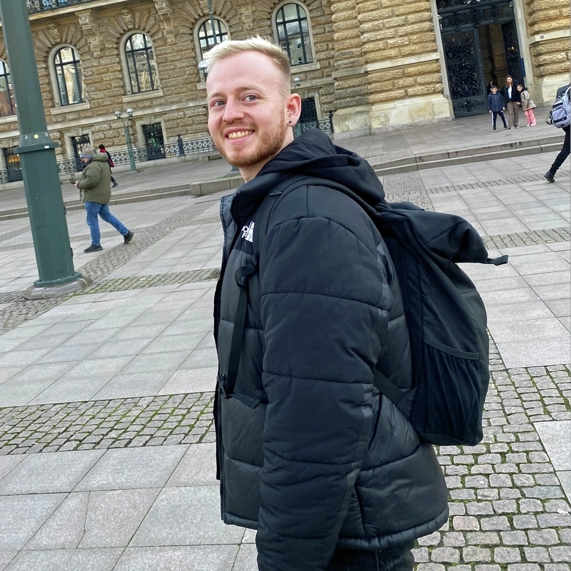 Porträt eines jungen Mannes vor einem historischen Gebäude