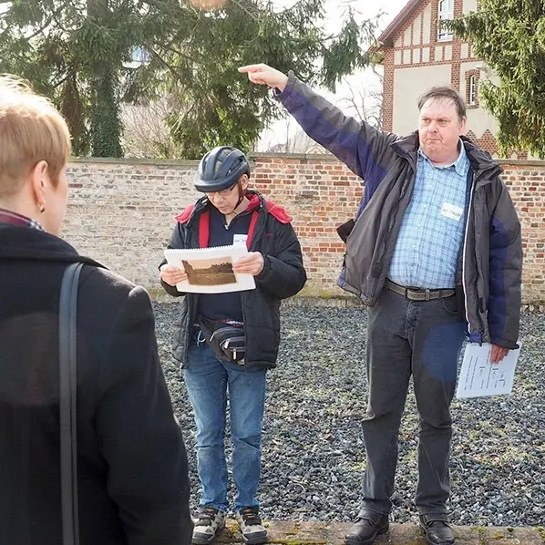 Drei Ehrenamtler mit Behinderung führen eine Besuchergruppe durch die T4-Gedenkstätte in Brandenburg