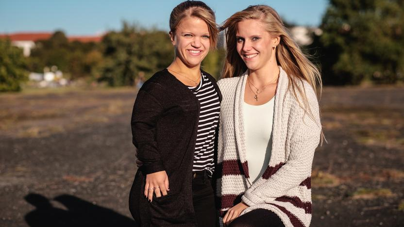 Porträtaufnahme von Jacqueline und Nicole, die beide in die Kamera lächeln.