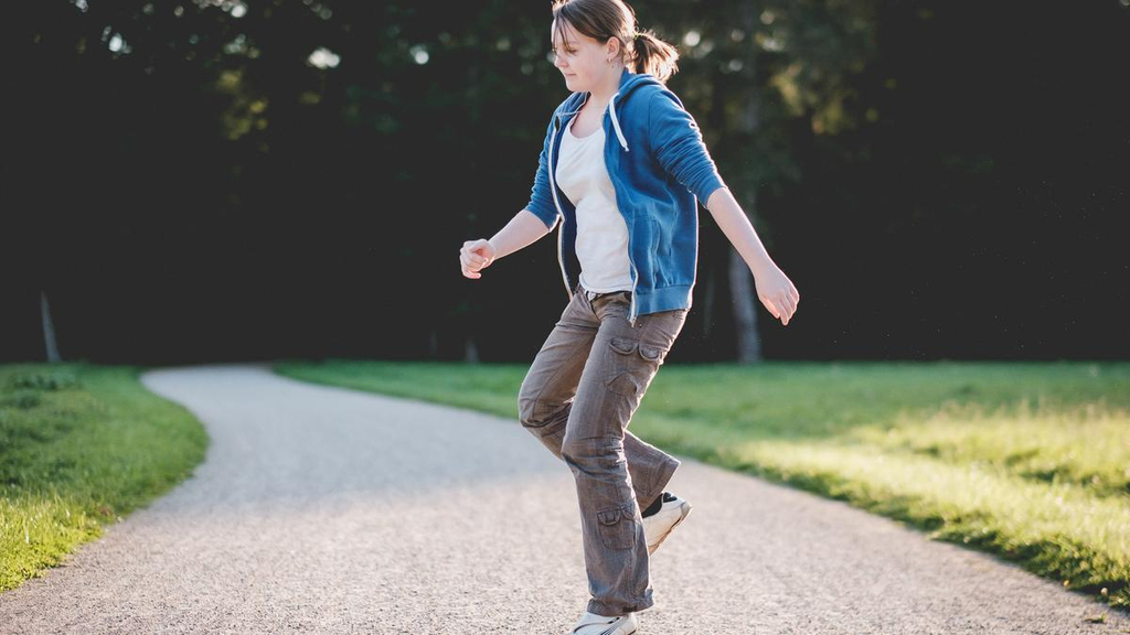Frauke auf einem Bein hüpfend im Park.