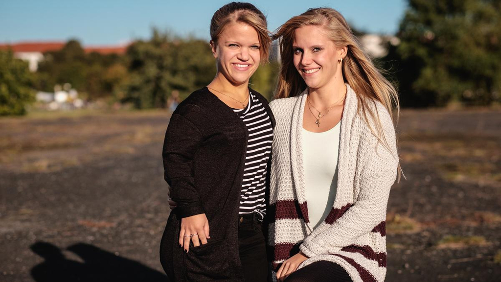 Porträtaufnahme von Jacqueline und Nicole, die beide in die Kamera lächeln.