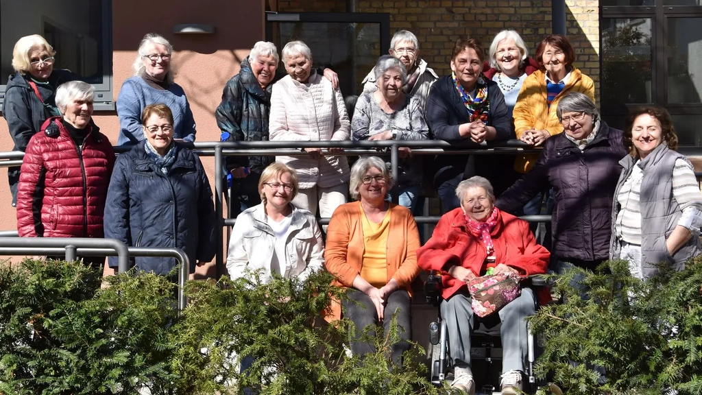 Eine Gruppe von älteren Frauen stehen zusammen für ein gemeinsames Foto.