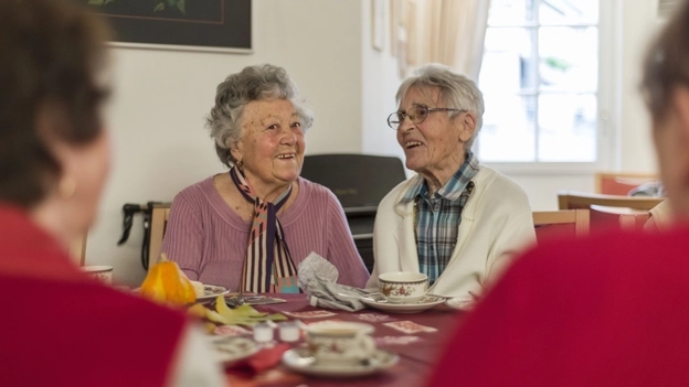Zwei ältere Frauen unterhalten sich beim Kaffee trinken.