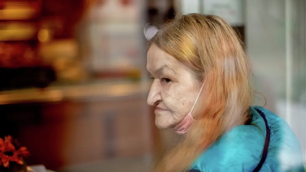 Eine ältere Frau schaut nachdenklich aus dem Fenster