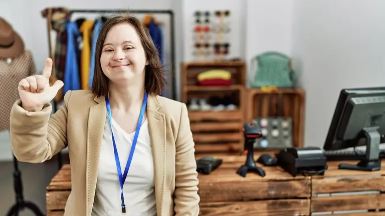 Junge Verkäuferin mit Down-Syndrom in Kleidergeschäft