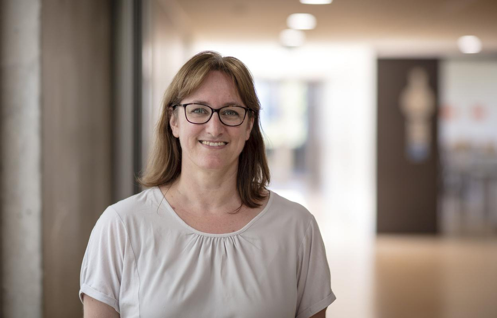 Andrea Hültz steht im Schulflur und lächelt in die Kamera.