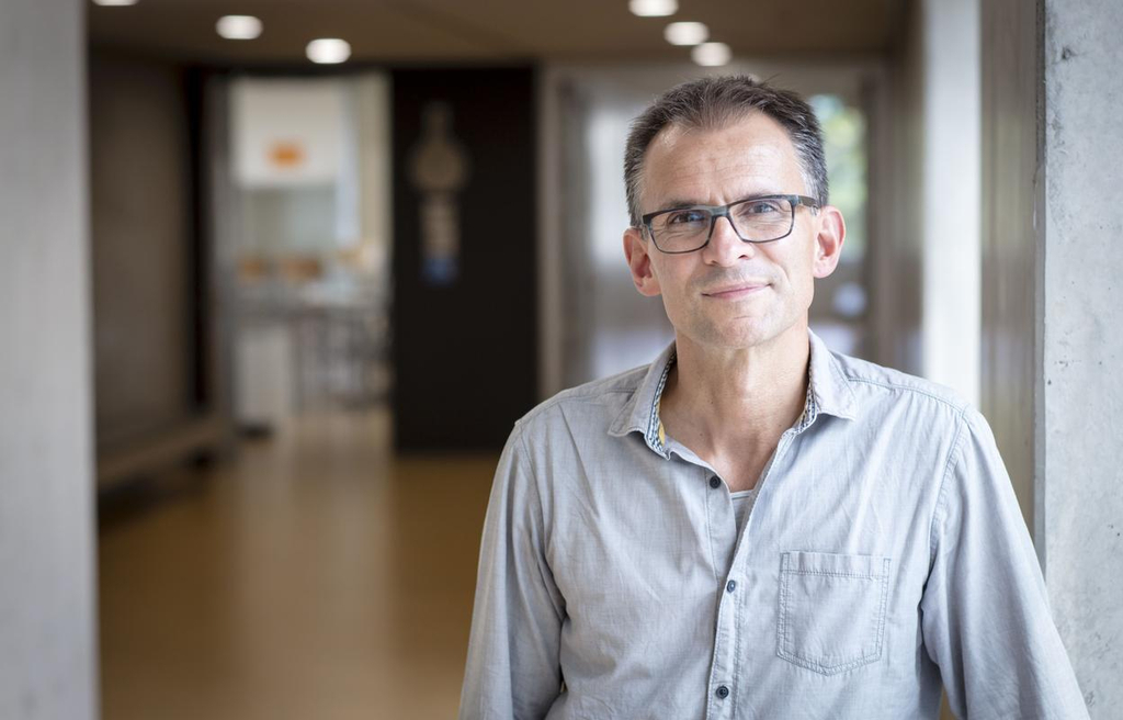 Peter Philipzen steht im Schulflur und lächelt in die Kamera.