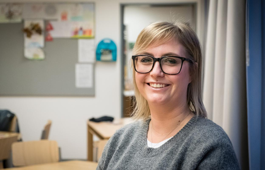 Josephine Thomas steht in einem Klassenzimmer und lächelt in die Kamera.